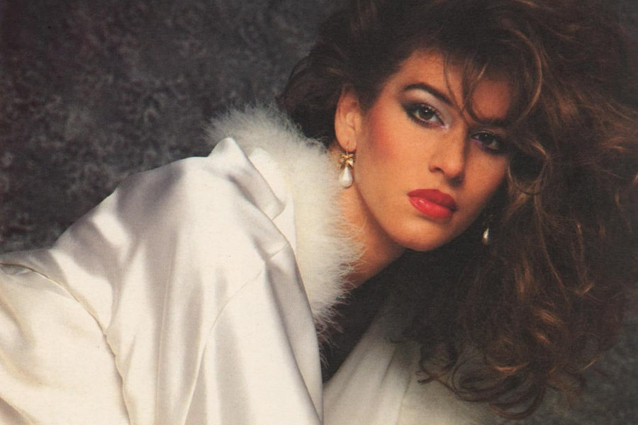 Close-up of Eva Robin’s with red lipstick, statement earrings, and 80s-style makeup.