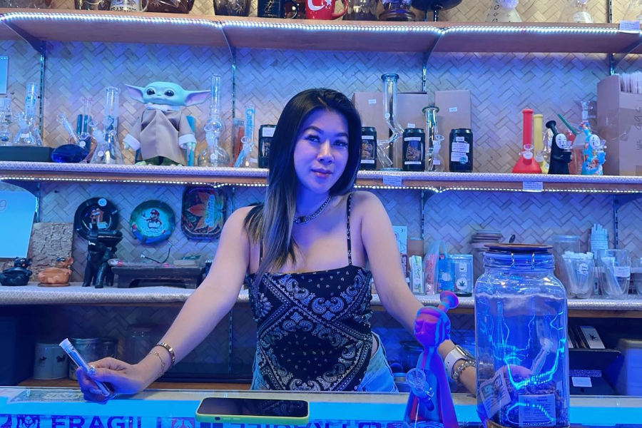 Bar interior at Soi Paradise Phuket showing a woman behind the counter with drinks, glass jars and vibrant nightlife decor.